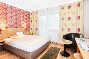 LautertalにあるLandhotel Kuralpe Kreuzhofのベッドとデスクが備わるホテルルームです。