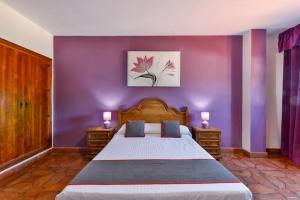 - une chambre avec un grand lit aux murs violets dans l'établissement Hostal Alfonso XI, à Guadalupe