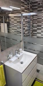 ein Badezimmer mit einem weißen Waschbecken und einem Spiegel in der Unterkunft Super Apartamento en playa de la Pineda in La Pineda