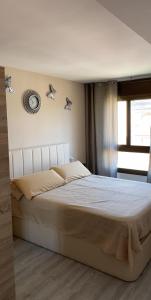 een bed in een slaapkamer met een klok aan de muur bij Super Apartamento en playa de la Pineda in La Pineda