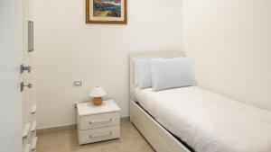 una camera bianca con letto e comodino di Welcomely - La Maddalena 20 ad Alghero