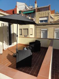 einen Regenschirm auf einem Balkon mit einem Tisch und einem Stuhl in der Unterkunft Apartamentos Barcelona - Iberia in Barcelona