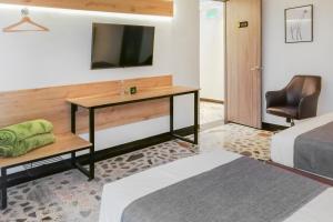 佩雷拉HOTEl AIRPORT PEREIRA的一间卧室配有书桌,墙上配有电视