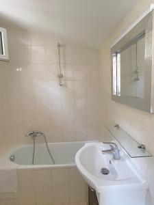 uma casa de banho branca com um lavatório e uma banheira em Propriété Malva appartement agava em Alata