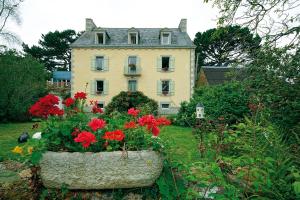 una casa grande con flores rojas delante de ella en Maison de Kersalomon, en Concarneau