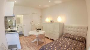 a bedroom with a bed and a table and a kitchen at SeaYouSoon Inn Cannes - Studios in Cannes