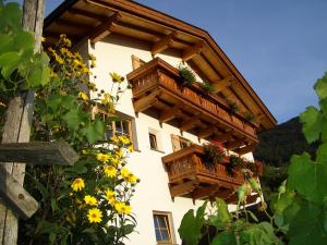 ein Gebäude mit Holzbalkonen und Blumen darauf in der Unterkunft Lafreiderhof in Kastelruth