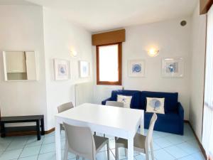 a dining room with a white table and a blue couch at Villa Santin Carraro Immobiliare - Family Apartments in Lido di Jesolo