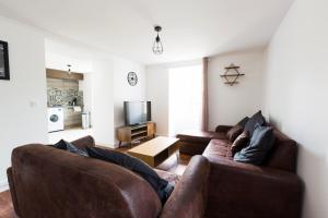 a living room with two brown couches and a television at Au Refuge Hyper centre Joigny in Joigny