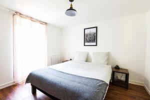 Un dormitorio con una cama con sábanas blancas y una ventana. en Au Refuge Hyper centre Joigny, en Joigny