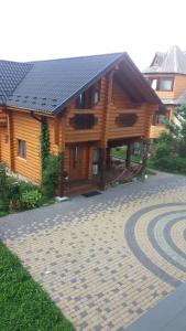 ein großes Holzhaus mit einem Steinweg davor in der Unterkunft Nota Bene Mykulychyn in Mykulytschyn