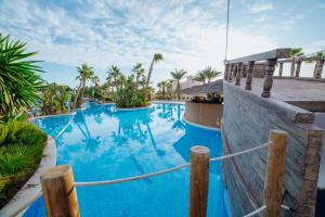 una piscina con agua azul y palmeras en Alannia Guardamar, en Guardamar del Segura