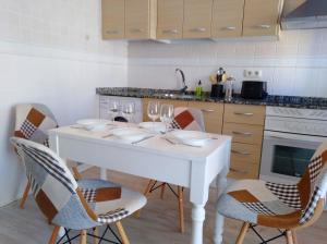 uma cozinha com uma mesa branca e cadeiras com copos de vinho em Piso Pescaíto - Tarifa Centro em Tarifa