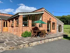 ein Backsteinhaus mit einem Tisch und einem Sonnenschirm in der Unterkunft The Old Bull Pen in Abergavenny