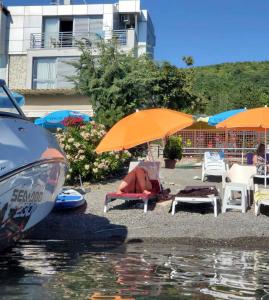 a woman sitting on a chair under an umbrella next to the water at Vila Ineks Ohrid in Ohrid