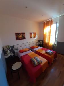 a bedroom with two beds and a table and a window at La Dimora di Nadine in La Spezia