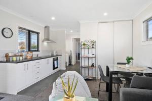 a white kitchen with a table and a dining room at Zoo Villas: Villa Giraffe - Central Wynyard in Wynyard