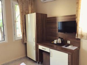 a small kitchen with a refrigerator and a tv at Dove Apart Hotel in Fethiye