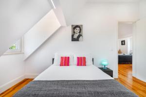 a white bedroom with a white bed with red pillows at WHome | Premium River View Apartment in Lisbon