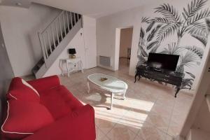 a living room with a red couch and a table at la maison de maxime in Courcelles-lès-Gisors