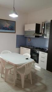 a kitchen with a white table and white chairs at Appartamento Nausicaa in Lamezia Terme