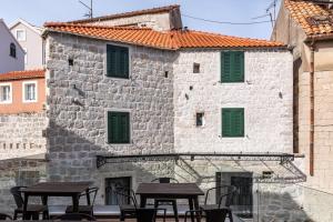 ein altes Steingebäude mit grünen Rollläden und Tischen in der Unterkunft Historic Plaza Varos Split in Split