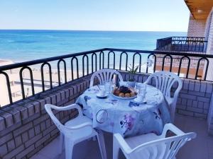einen Tisch mit einem Teller Essen auf einem Balkon mit Strand in der Unterkunft Bernat Vidaber Primera Línea in Oropesa del Mar