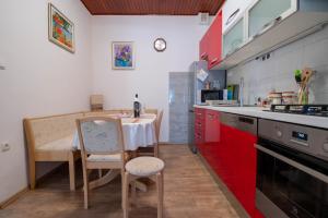 a kitchen with a table and red cabinets at Apartman Ivan in Drniš