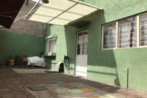 une maison verte avec une porte blanche et un bâtiment dans l'établissement Casa Matlaltlkali - Zonas Arqueologicas y Parques Temáticos, à Mexico