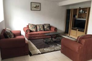 a living room with two couches and a tv at Casa Matlaltlkali - Zonas Arqueologicas y Parques Temáticos in Mexico City