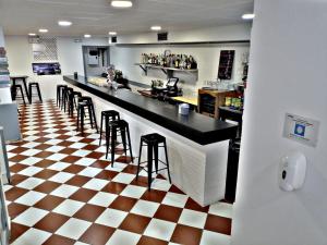 a bar with stools in a restaurant with a checkered floor at Pension El Figon in Santander