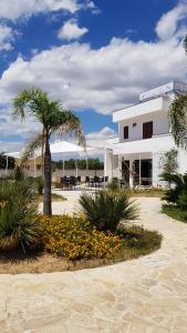 a building with a palm tree and flowers in front of it at Hotel Costa Blu in Sant'Isidoro