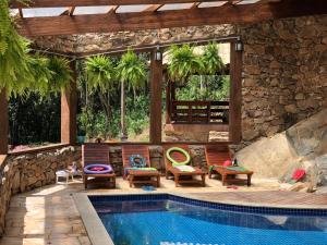 a swimming pool with chairs next to a house at Hotel Pousada Riacho da Areia in Águas de Lindoia
