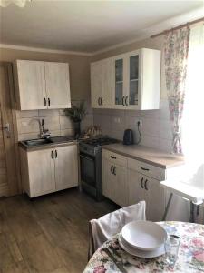 a small kitchen with white cabinets and a table with a table sidx sidx at Domek pod Lipą in Narol