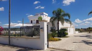 ein weißes Gebäude mit einem Zaun und einer Palme in der Unterkunft Hotel Costa Blu in Sant'Isidoro