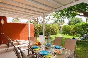 a table with plates of food on a patio at Flamboyant Tree Garden Holiday Home in Maspalomas