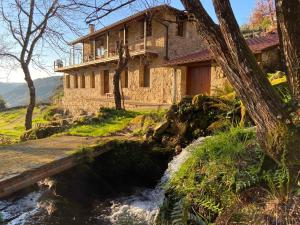 ein Gebäude neben einem Fluss vor einem Haus in der Unterkunft Lujosa casa en la Ribeira Sacra in Acova