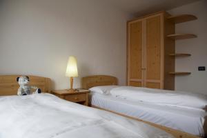 - une chambre avec 2 lits et un ours en peluche sur une table de nuit dans l'établissement Residence Miramonti, à Daiano