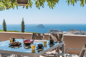 a table with a bowl of fruit and glasses of orange juice at Villa Iris in Livadi