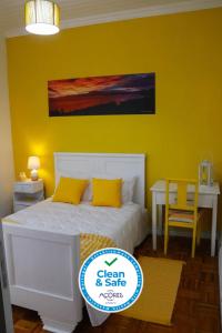 a bedroom with a white bed and a yellow wall at Vista do Norte - Northern View! in Santo António