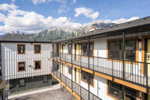 un immeuble d'appartements avec balcon donnant sur les montagnes en arrière-plan dans l'établissement Basecamp Suites Canmore, à Canmore