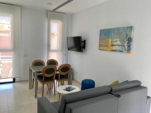 sala de estar con sofá y mesa con sillas en Apartamentos Rivero 8, en Sevilla