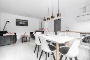 een witte eetkamer met een witte tafel en stoelen bij Apartament Matejki II - Unique Apartments in Szczecin
