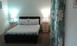 ein Schlafzimmer mit einem Bett und zwei Nachttischen mit Lampen in der Unterkunft Necarne Manor Apartment in Irvinestown