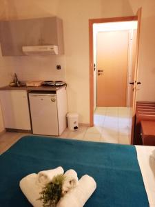 a room with a kitchen with towels on a bed at Hotel Eleni in Paralia Dionysiou
