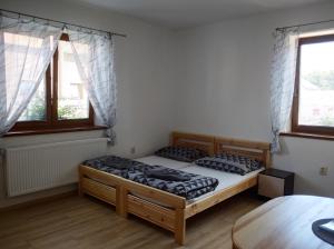 2 Betten in einem Zimmer mit einem Tisch und 2 Fenstern in der Unterkunft Apartmány Opolany in Opolany
