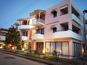 un edificio de apartamentos rosa por la noche en Hotel Eleni, en Paralia Dionisiou