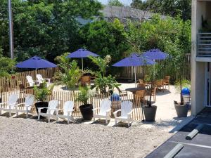 un patio con sillas, mesas y sombrillas en Crosswinds Motel en Rehoboth Beach