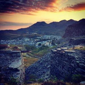 a view of a city from a mountain at sunset at Snowdonia miners cottage in Blaenau-Ffestiniog