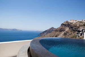 a swimming pool on a cliff next to the ocean at Porto Fira Suites in Fira